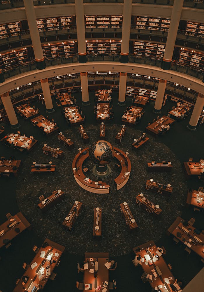 Mastering the First Impression: Your intriguing post title goes here Captivating aerial view of a modern library interior with numerous desks and a central globe, buzzing with activity.