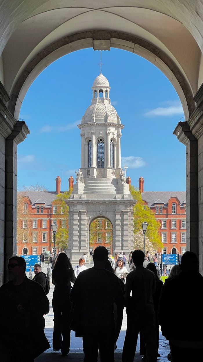 Home View of the iconic Campanile in Trinity College, Dublin, framed by an archway on a sunny day.